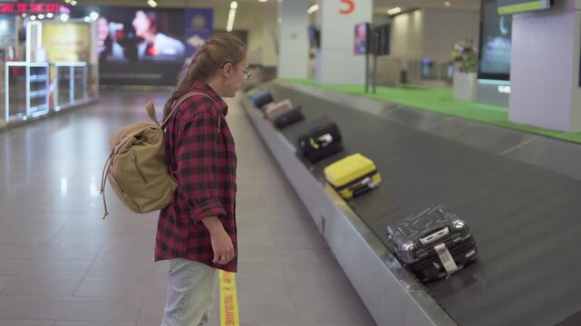 Female tourist with backpack is waiting her luggage in airport