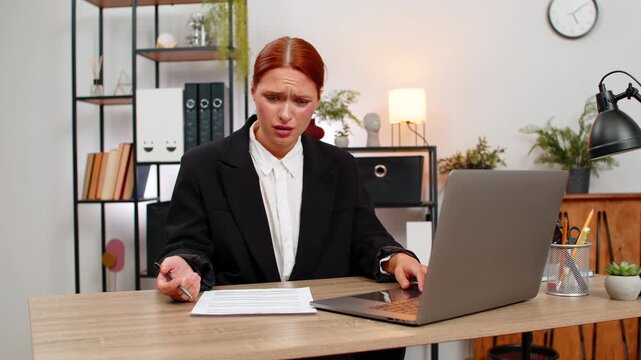 Young businesswoman at home office sees debit credit error on laptop and crumples paper feeling intense panic. Freelancer girl at table corrects finance report hoping to fix balance and calm mind soon