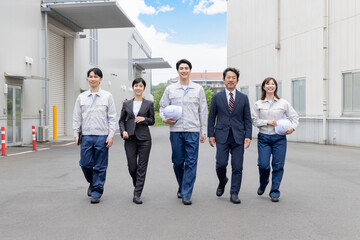 Fototapeta premium 工場の前を歩く作業員グループ