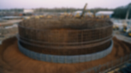 Naklejka premium Blurred background of Large diameter bored pile cage prefabrication on ground surface, cylindrical reinforcement cage with spiral ties and longitudinal bars extending over.