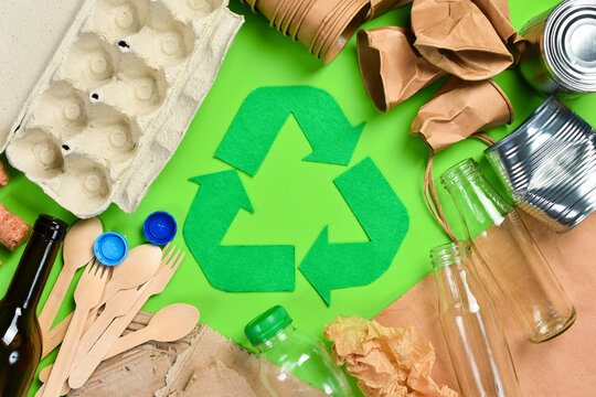 Green background with recycling symbol. Flat lay of various types of garbage. Top view.