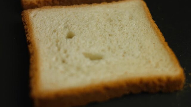 Two slices of white bread toasting in a pan