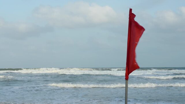 A red flag with heavy windy condition, it is the bad weather warning sign, do not swimming in the sea. Safety sign and symbol.
