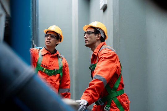 Two men in orange safety gear are looking at a pipe