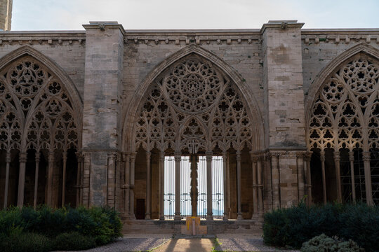 Gothic cloister of La Seu Vella Cathedral in Lleida, Catalonia, Spain. Ornate stone tracery windows of the historic old cathedral on a sunny day.