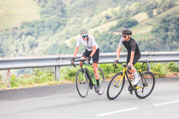 Naklejka premium Cyclists man and woman couple riding together climbing a mountain at the Aiako Harriak natural park in the Basque Country.