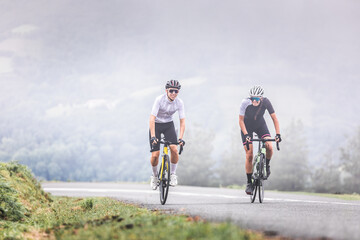 Fototapeta premium Cyclists man and woman couple riding together climbing a mountain at the Aiako Harriak natural park in the Basque Country.