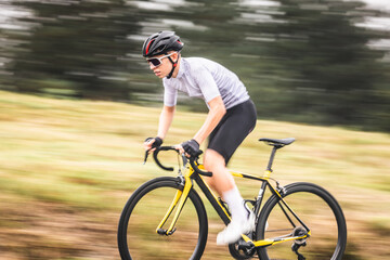 Obraz premium Young caucasian man riding a bike climbing a hill
