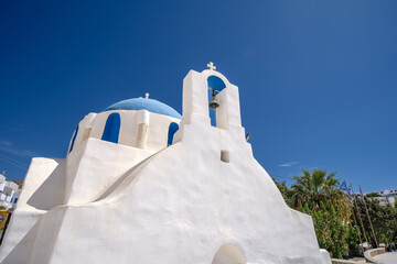 View of a picturesque whitewashed Greek Orthodox chapel in Ios Greece with a cross and a bell