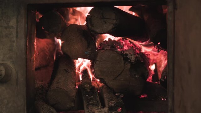 Logs of wood burning with red fire flame in stove close-up