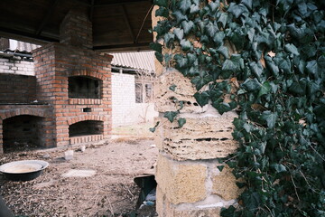 Fototapeta premium Winter rural yard at sunset. Snow-covered garden with bare fruit trees, old brick house with attic, netting fence,