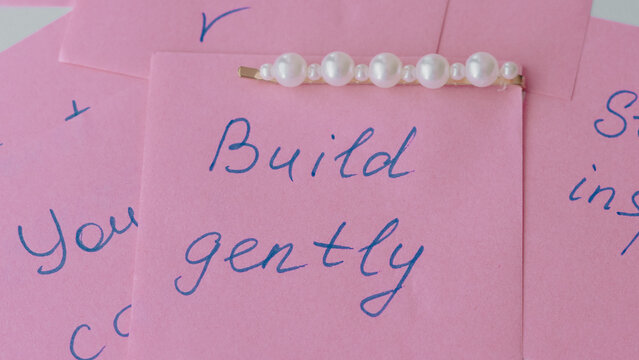 Pink sticky notes with handwritten messages and decorative pearl hair accessory