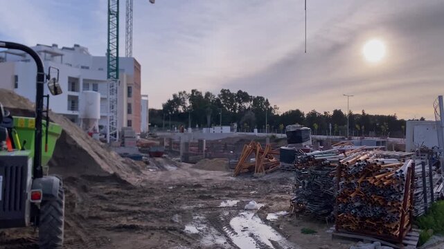 Building new homes and infrastructure, showing ongoing construction work, heavy equipment, and building materials at sunrise