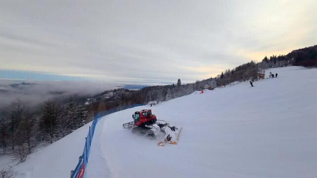 Dynamic first-person view drone chase of a snowcat preparing ski slopes at Jaworzyna in Szczyrk, Polish Beskid Mountains. Cinematic winter footage featuring mountain scenery, fresh snow, and resort ma