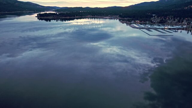 Clouds mirrored across still lake surface creating dramatic sky reflection at twilight