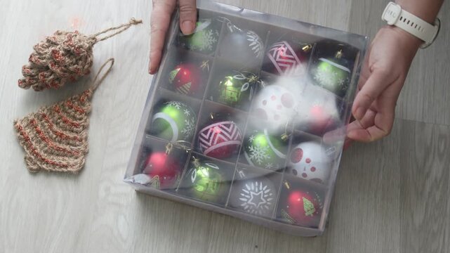 Top view of Holiday Cleanup Completed features hands closing transparent lid on storage box filled with red and green ornaments. Holiday Cleanup Completed routine for organized seasonal decor storage.