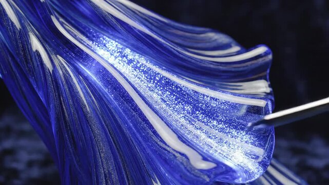 Close up of a hand touching a blue glass art sculpture