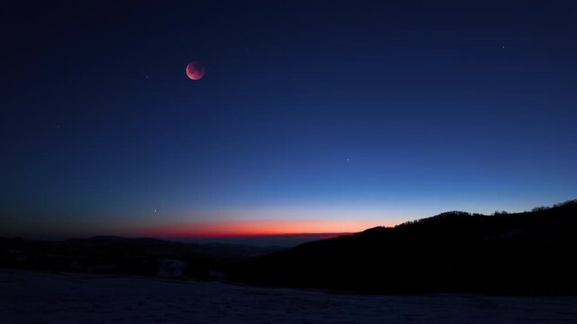 Blue hour time with lunar eclipse, stars and planets above landscape silhouettes.