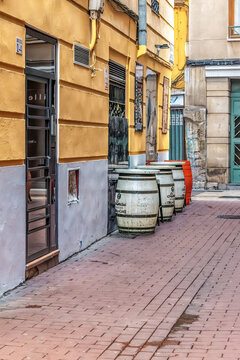 Vertical view of wine barrel tables on Calle de la Santa Cruz in the historic El Tubo district. Traditional outdoor seating of Bodegas Almau restaurant. Zaragoza, Spain - November 29, 2021
