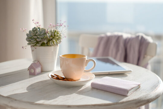 Cinematic kitchen table scene with mortgage rate notebook, tablet, espresso mug, succulent and copper coins, pastel tones and oval bokeh for copy overlay
