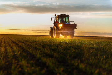 Tractor spreading artificial fertilizers in field