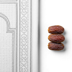 Three Dates Fruits Stacked Next to White Islamic Prayer Rug Detail