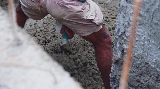 Worker mixing cement mortar for RCC wall plastering work at construction site. day time, stable shot, top down shot, 4k.