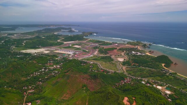 Aerial drone video of Mandalika Lombok Indonesia with MotoGP circuit curves beside turquoise ocean reefs sandy bays green hills and coastal roads wide cinematic travel panorama in 4k