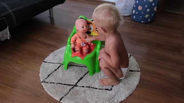 A 2 or 3 year old child sits a doll on the potty, a concept for potty training and weaning.
