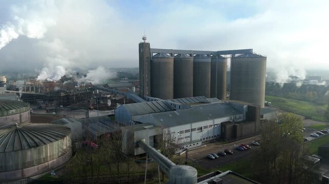Aerial drone view of Bury St Edmunds sugar factory with huge silos and smoking chimneys during winter campaign in Suffolk United Kingdom