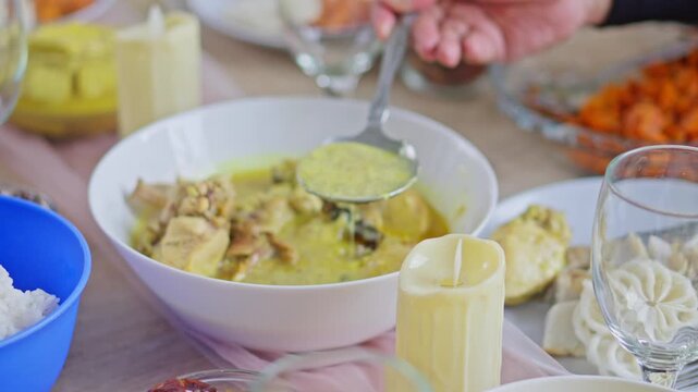 Close-up of Serving Indonesian chicken opor ayam into plate during an Eid al-Fitr family feast