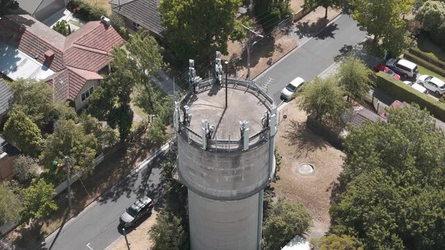 Drone video capturing an aerial perspective of the Karen Reece water tower in Australia. The striking tower stands amidst a suburban setting, surrounded by lush greenery and roads.