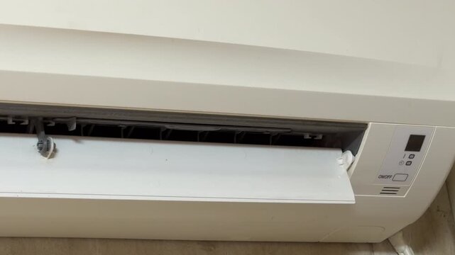 The white air conditioning unit closes its vent as the power is cut. This movement triggers a clear electronic beep followed by the gradual silencing of the internal fan's hum.