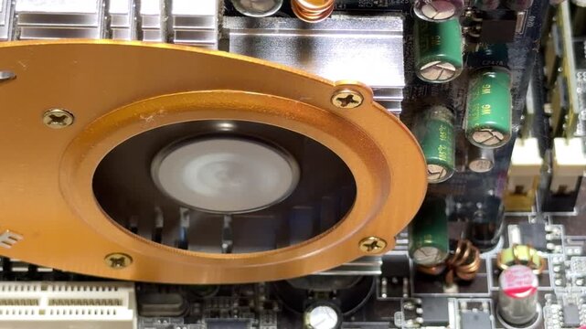 A golden GPU cooler fan rotates at high speed over a circuit board. The spinning blades create a continuous white noise hum and a soft rushing air sound.