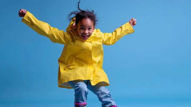 Joyful child jumping in yellow raincoat studio