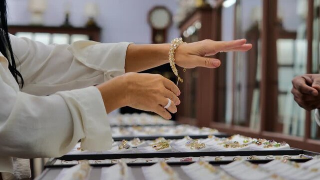 Woman Customer Trying Ring Jewelry Store Luxury Shopping Closeup of Hands Selecting Diamond Ring in Boutique Showcase with Elegant Interior and Warm Light