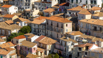 Obraz premium Aerial view of a traditional Italian village, showing a mix of historic buildings with terracotta-tiled roofs. The shot highlights the dense urban layout, with glimpses of balconies and narrow spaces.