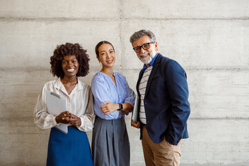 Portrait of confident male and female business professionals smiling while standing together...