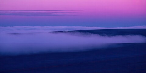 Obraz premium A serene mountain landscape with fog rolling in at sunset