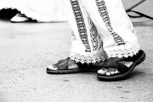 Cal&ccedil;a branca de renda e chinelo de couro. 