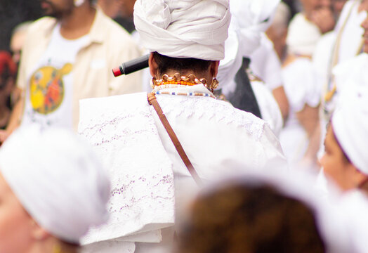 M&atilde;e de santo vestida de branco com turbante na cabe&ccedil;a. 
