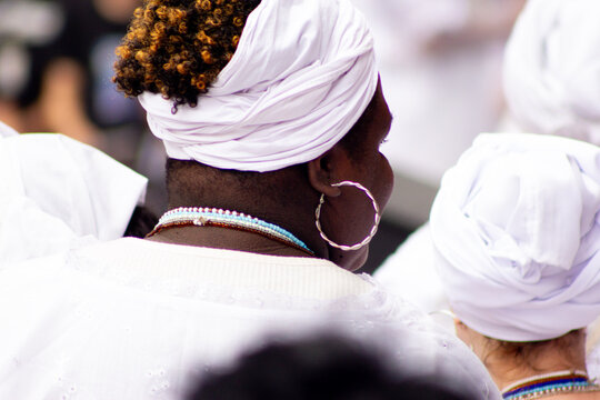 M&atilde;e de santo vestida de branco com turbante na cabe&ccedil;a. 