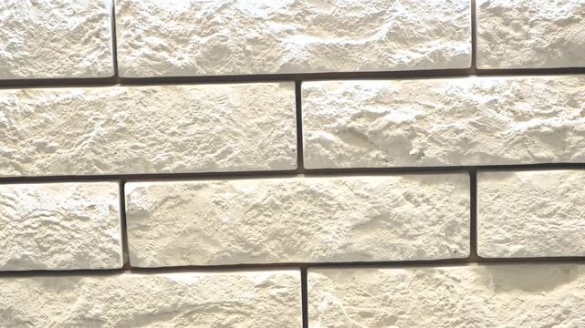 Textured white stone wall with rectangular blocks arranged in a pattern. The surface appears rough and uneven, suitable for backgrounds or architectural designs.