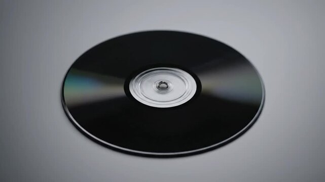 Close-up of a spinning black CD or DVD disc on a grey background, technology concept