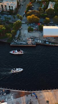 Four boat move slowly by the river near the bridge. Drone approaching one of the vehicles in Miami, Florida, USA. Vertical video