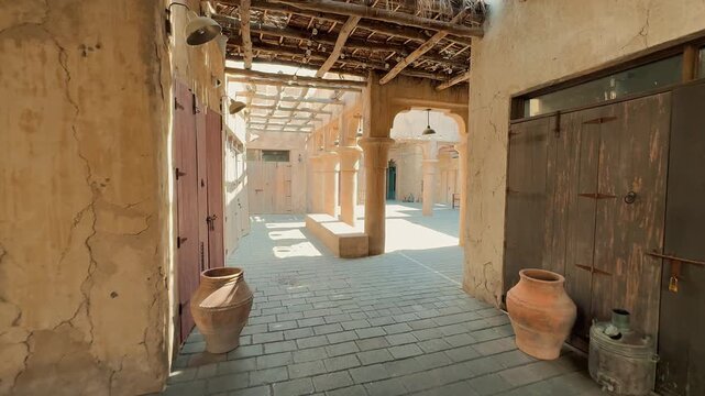 Scenic views of Dubai's Al Seef heritage district featuring traditional Arabian architecture, wind towers, narrow alleyways, and waterfront scenery along the creek during a sunny day.


