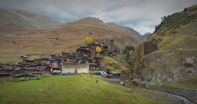 Aerial drone approach to the historic Dartlo village in Tusheti, Georgia; featuring traditional stone houses, ancient towers, and scenic mountain landscapes.