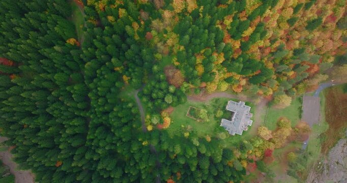 Aerial top-down view of Stalin's abandoned summer house in Racha, Georgia, surrounded by autumn colors. Camera slowly descends towards the building.