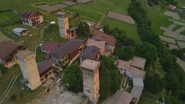 Aerial pan glides over medieval Svan stone towers and houses in Ushguli, Upper Svaneti, Georgia, down to a braided river, then pulls back to snow capped peaks.