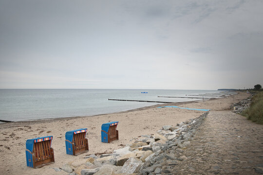 Weg hinunter zum Sandstrand an der Ostsee mit drei blauen Strandk&ouml;rben vor Felsbrocken